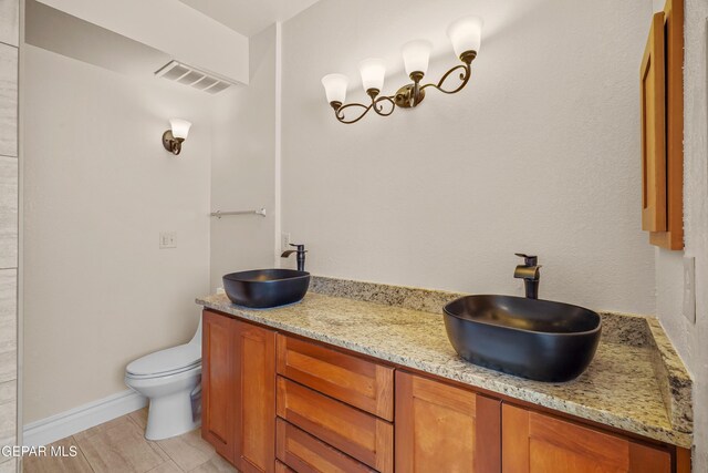 bathroom featuring double vanity, toilet, and baseboards