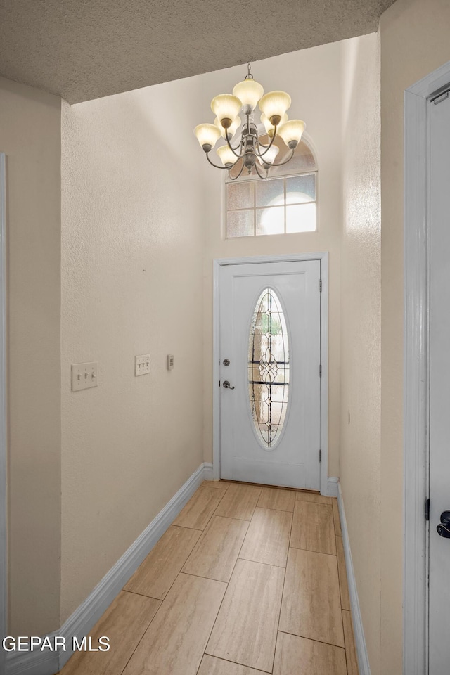 doorway to outside featuring a chandelier, baseboards, wood tiled floors, and a textured ceiling