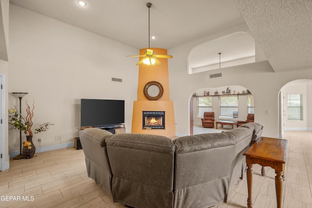 living room featuring arched walkways, baseboards, a high ceiling, a fireplace, and recessed lighting