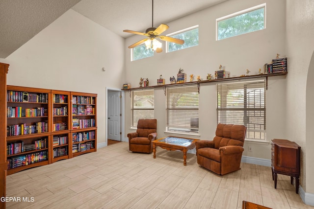 sitting room featuring a ceiling fan, a high ceiling, and baseboards