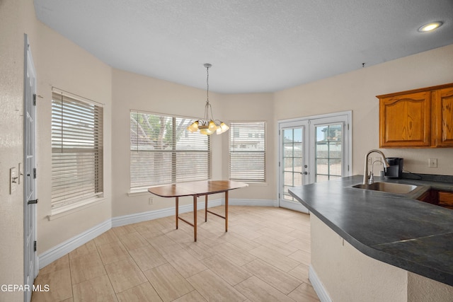 kitchen featuring a sink, dark countertops, brown cabinetry, baseboards, and a textured ceiling
