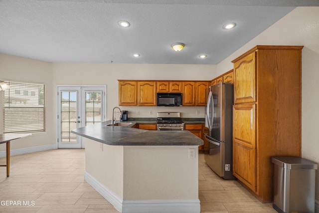 kitchen featuring appliances with stainless steel finishes, a sink, brown cabinets, recessed lighting, and dark countertops