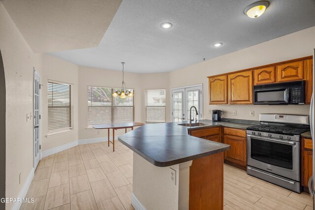 kitchen with stainless steel range with gas cooktop, black microwave, a sink, dark countertops, and a textured ceiling