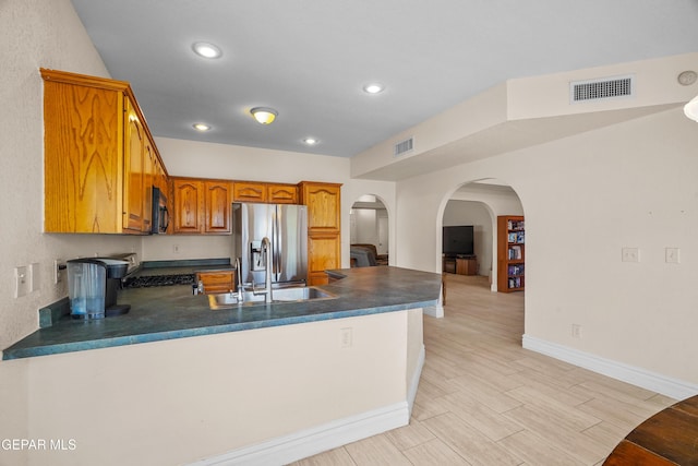 kitchen with stainless steel fridge with ice dispenser, black microwave, dark countertops, a peninsula, and a sink