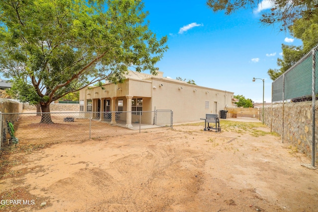 rear view of property featuring a fenced backyard and stucco siding