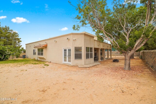 rear view of property with stucco siding, french doors, and fence