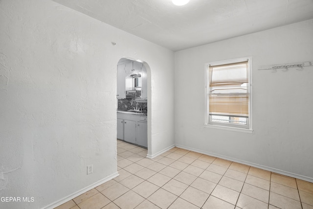 3817 La Luz Ave, El Paso, TX 79903 - unfurnished room with light tile patterned flooring, arched walkways, a sink, and baseboards