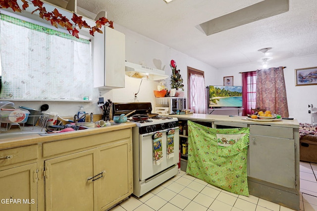 564 Chula Vista St, El Paso, TX 79915 - kitchen featuring white gas range oven, under cabinet range hood, light tile patterned floors, a peninsula, and a textured ceiling