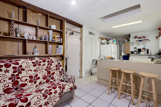 564 Chula Vista St, El Paso, TX 79915 - kitchen featuring freestanding refrigerator, light tile patterned flooring, open shelves, a textured ceiling, and a breakfast bar area