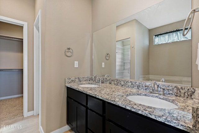 14172 Peyton Edwards Ave, El Paso, TX 79938 - bathroom featuring a spacious closet, double vanity, a stall shower, wood finished floors, and baseboards