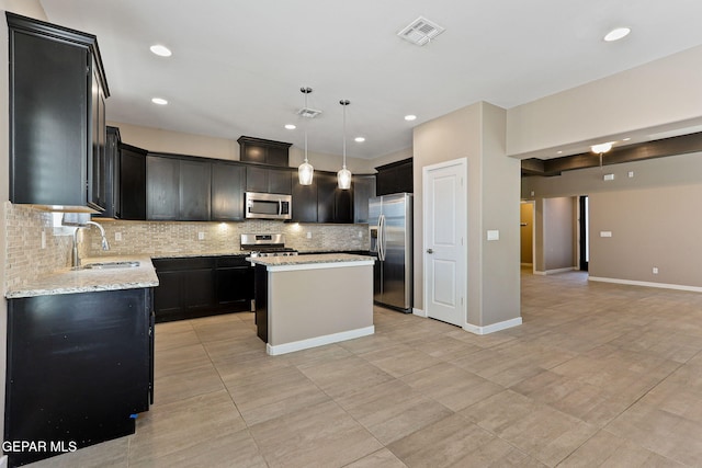 14172 Peyton Edwards Ave, El Paso, TX 79938 - kitchen with appliances with stainless steel finishes, a sink, backsplash, a kitchen island, and light stone counters