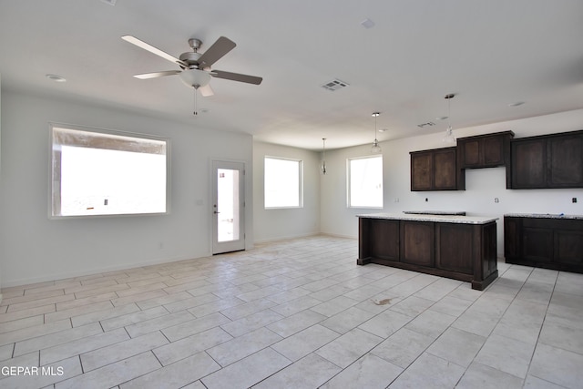 15341 Idea Ln, El Paso, TX 79938 - kitchen featuring ceiling fan, dark brown cabinets, open floor plan, a center island, and light countertops