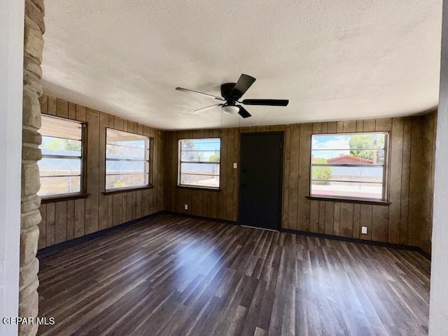 5017 Sierra Madre Dr, El Paso, TX 79904 - empty room with dark wood-type flooring, baseboards, a textured ceiling, wood walls, and a ceiling fan