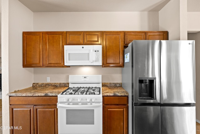 10740 White Sands Dr, El Paso, TX 79924 - kitchen featuring white appliances, brown cabinetry, and dark stone countertops