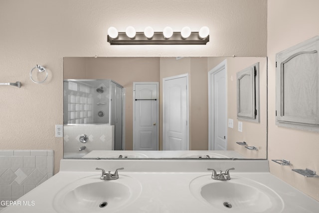 10740 White Sands Dr, El Paso, TX 79924 - full bathroom featuring a stall shower, double vanity, and a textured wall
