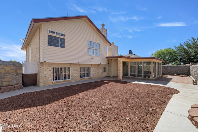 10740 White Sands Dr, El Paso, TX 79924 - rear view of property featuring a sunroom, brick siding, a patio area, and a chimney