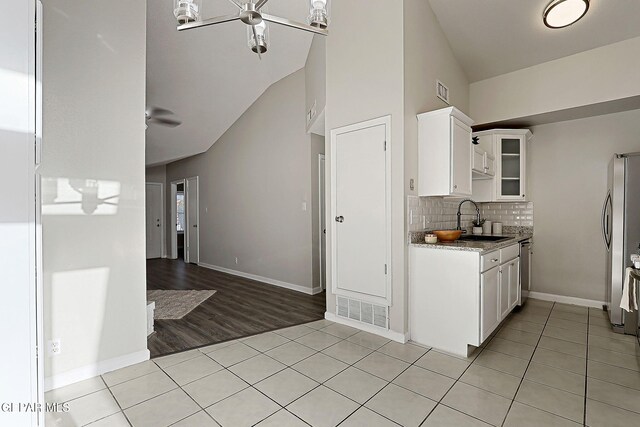 819 Los Surcos Rd, El Paso, TX 79907 - kitchen with a sink, appliances with stainless steel finishes, light tile patterned floors, glass insert cabinets, and decorative backsplash