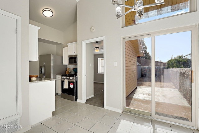 819 Los Surcos Rd, El Paso, TX 79907 - kitchen featuring appliances with stainless steel finishes, high vaulted ceiling, light tile patterned flooring, white cabinetry, and baseboards