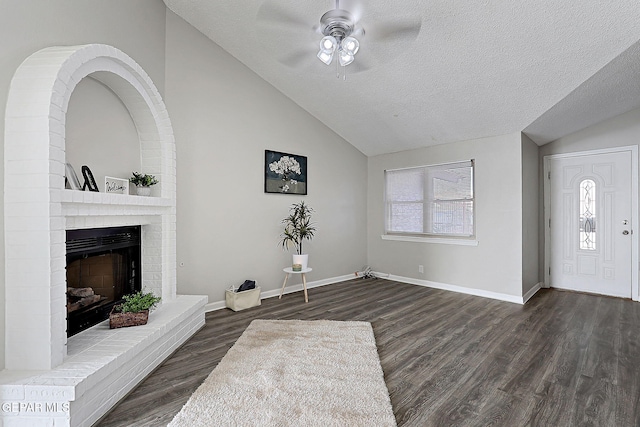 819 Los Surcos Rd, El Paso, TX 79907 - entrance foyer featuring lofted ceiling, a ceiling fan, dark wood-style flooring, a brick fireplace, and a textured ceiling