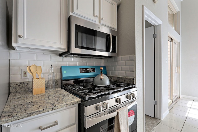819 Los Surcos Rd, El Paso, TX 79907 - kitchen featuring stainless steel appliances, decorative backsplash, light tile patterned floors, and light stone counters