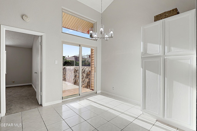819 Los Surcos Rd, El Paso, TX 79907 - unfurnished dining area with a chandelier, baseboards, light tile patterned flooring, light carpet, and a towering ceiling