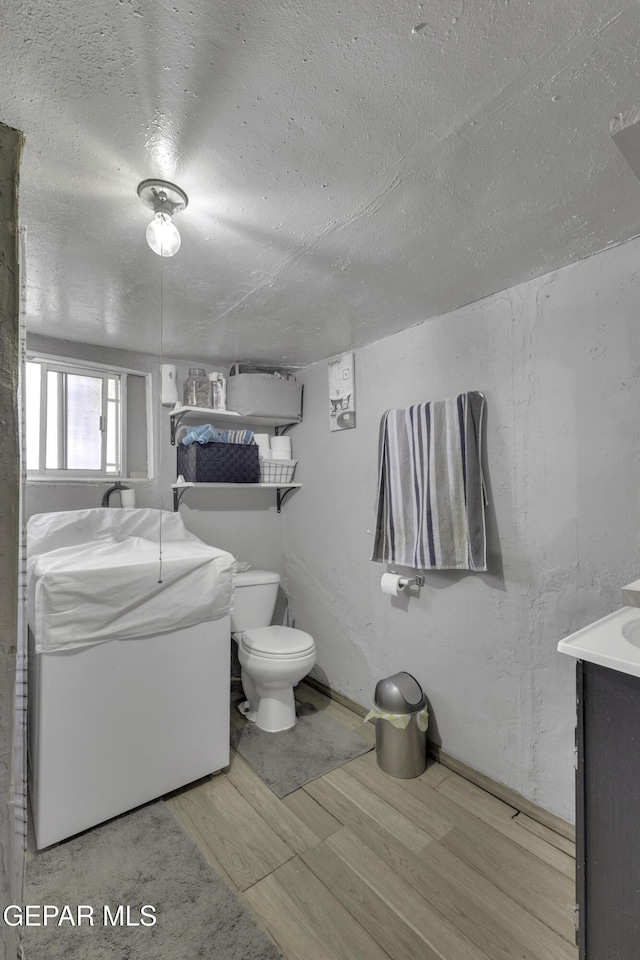 720 Johnson St, Fabens, TX 79838 - bathroom with wood finished floors, a textured ceiling, toilet, and vanity