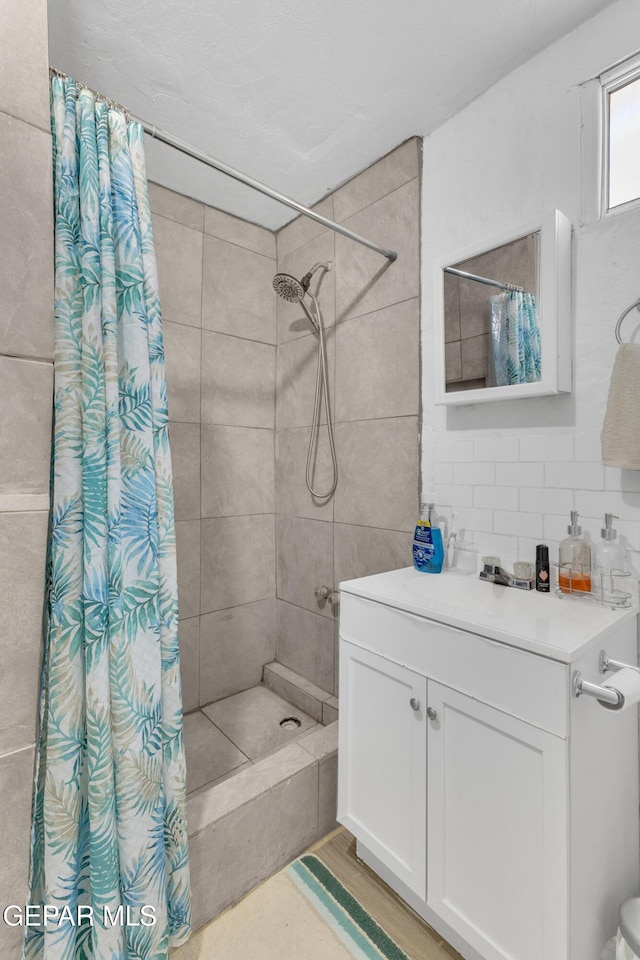 720 Johnson St, Fabens, TX 79838 - bathroom featuring a tile shower, vanity, and decorative backsplash
