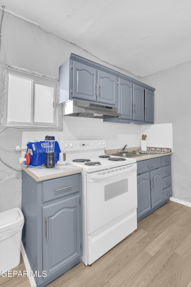 720 Johnson St, Fabens, TX 79838 - kitchen featuring white electric range oven, under cabinet range hood, light wood-style floors, tasteful backsplash, and light countertops