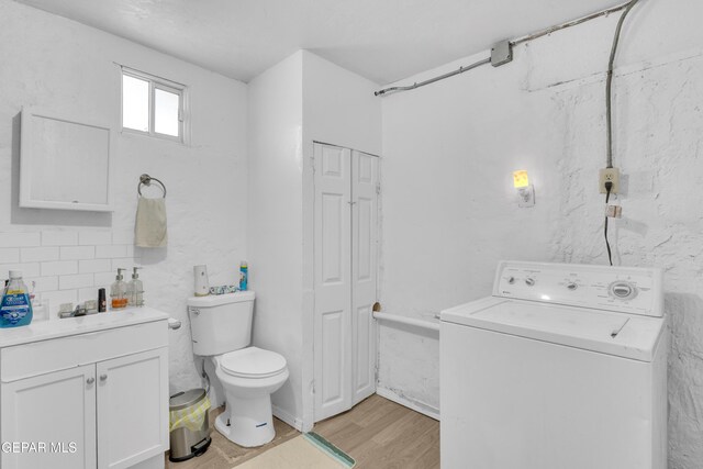 720 Johnson St, Fabens, TX 79838 - bathroom with washer / dryer, wood finished floors, toilet, vanity, and tasteful backsplash