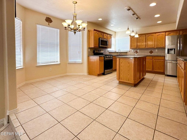 3081 Tierra Humeda Dr, El Paso, TX 79938 - kitchen featuring appliances with stainless steel finishes, a chandelier, a kitchen island, tasteful backsplash, and brown cabinetry
