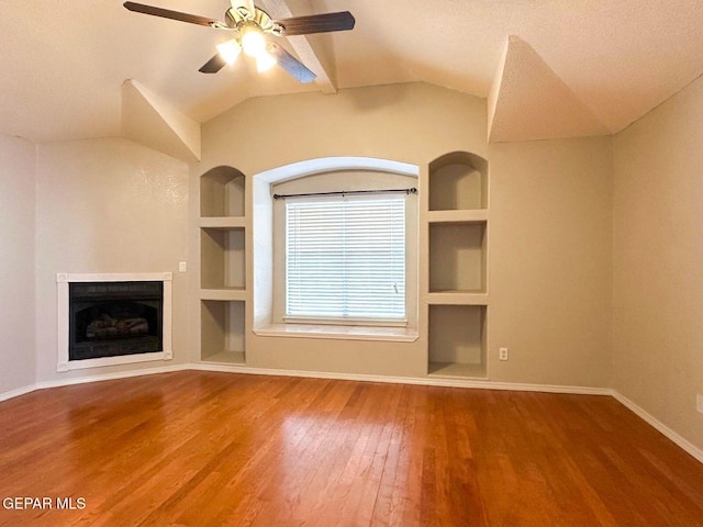 3081 Tierra Humeda Dr, El Paso, TX 79938 - unfurnished living room featuring built in shelves, wood finished floors, baseboards, a fireplace, and vaulted ceiling