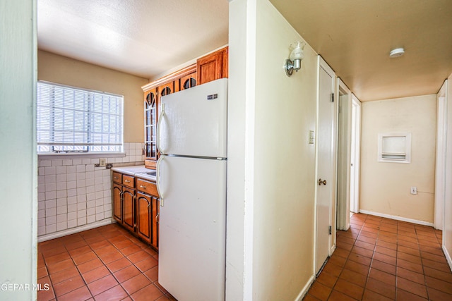 4209 Hercules Ave, El Paso, TX 79904 - kitchen featuring freestanding refrigerator, tile patterned floors, brown cabinetry, and tile walls
