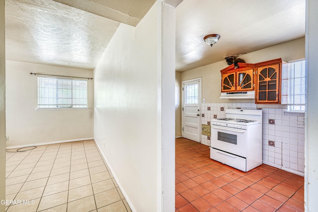 4209 Hercules Ave, El Paso, TX 79904 - kitchen featuring white gas stove, light tile patterned floors, under cabinet range hood, and a textured ceiling