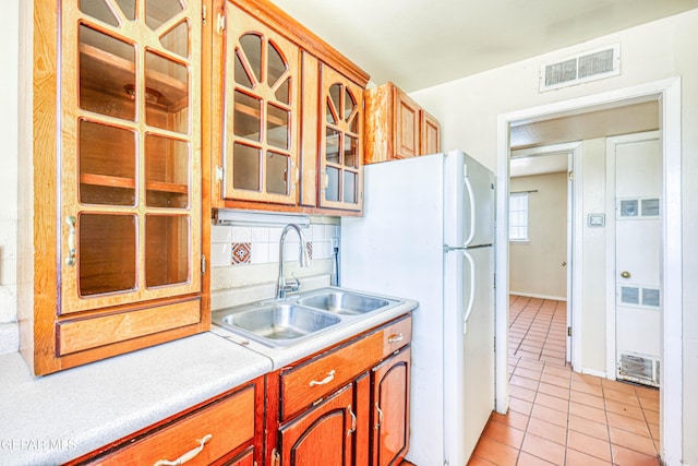 4209 Hercules Ave, El Paso, TX 79904 - kitchen with a sink, freestanding refrigerator, light countertops, light tile patterned flooring, and glass insert cabinets