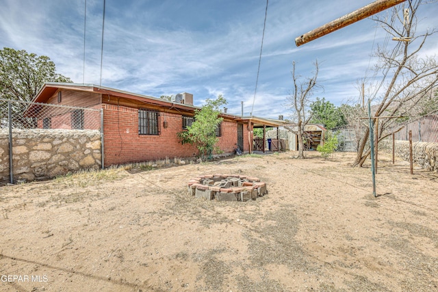 4209 Hercules Ave, El Paso, TX 79904 - rear view of property featuring an outdoor fire pit, brick siding, and fence