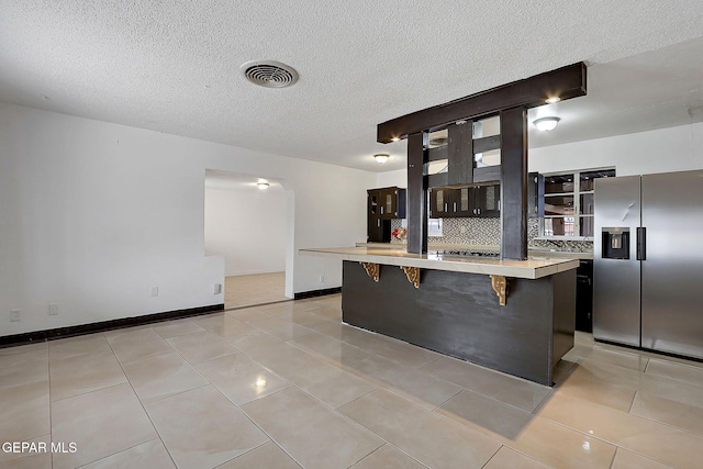 5713 Sanders Ave, El Paso, TX 79924 - kitchen with appliances with stainless steel finishes, light countertops, a breakfast bar area, arched walkways, and glass insert cabinets