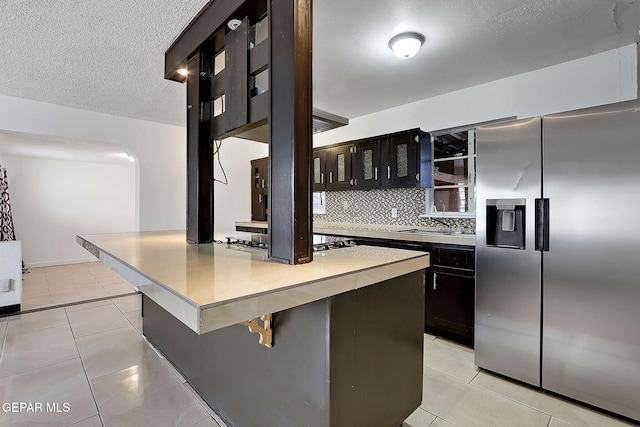 5713 Sanders Ave, El Paso, TX 79924 - kitchen with stainless steel refrigerator with ice dispenser, cooktop, light countertops, tasteful backsplash, and light tile patterned floors