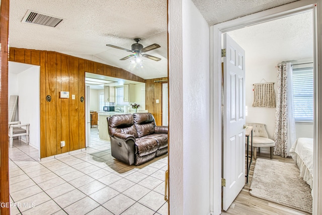 5137 Edmonton Ave, El Paso, TX 79924 - corridor with lofted ceiling, a textured ceiling, wooden walls, and light tile patterned floors