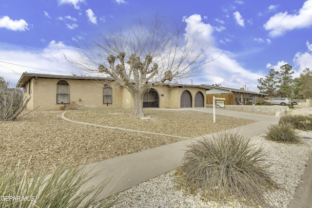 view of front of house featuring an attached garage, concrete driveway, brick siding, and fence
