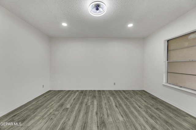 unfurnished room with wood finished floors, a textured ceiling, recessed lighting, and baseboards