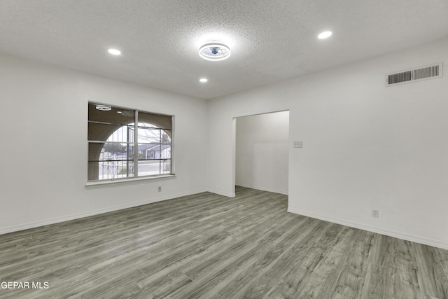 spare room featuring wood finished floors, recessed lighting, a textured ceiling, and baseboards