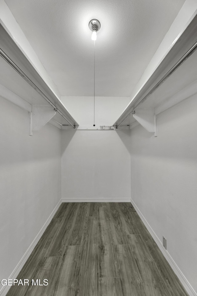 walk in closet with dark wood-style floors