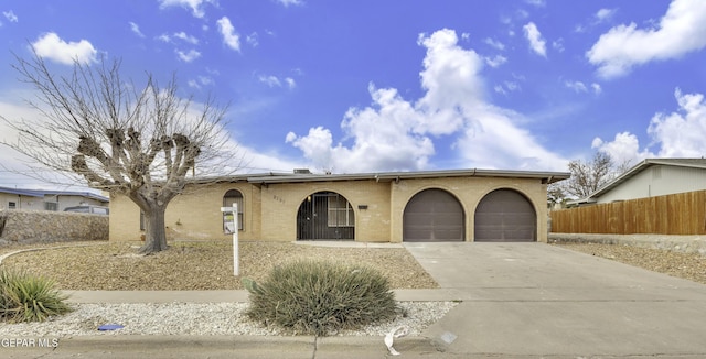view of front of property featuring an attached garage, brick siding, fence, and concrete driveway