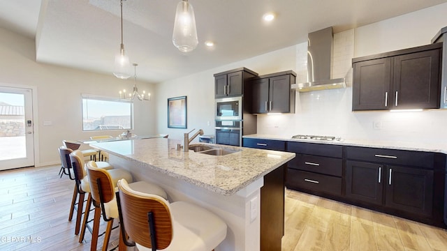 569 Logwood Ave, Canutillo, TX 79835 - kitchen featuring wall chimney exhaust hood, appliances with stainless steel finishes, a sink, light wood-style floors, and recessed lighting