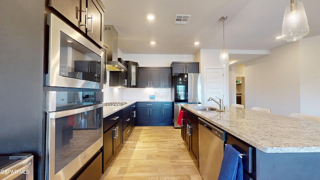 569 Logwood Ave, Canutillo, TX 79835 - kitchen with appliances with stainless steel finishes, light wood-type flooring, a sink, a large island with sink, and pendant lighting