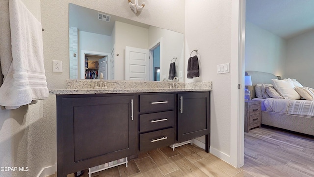 569 Logwood Ave, Canutillo, TX 79835 - bathroom featuring wood finished floors, double vanity, connected bathroom, and baseboards