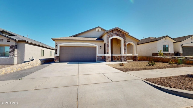 569 Logwood Ave, Canutillo, TX 79835 - view of front of house featuring stone siding, an attached garage, concrete driveway, and stucco siding