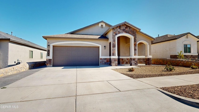 569 Logwood Ave, Canutillo, TX 79835 - view of front facade with stone siding, concrete driveway, an attached garage, and stucco siding