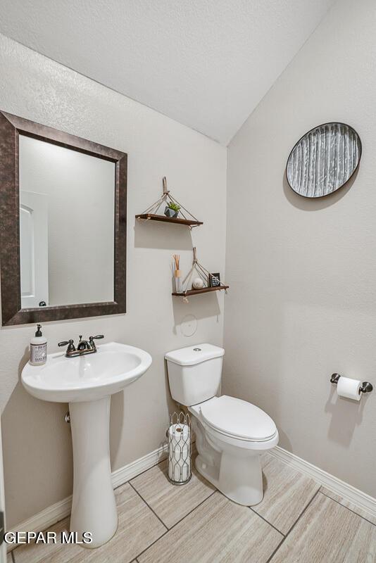 14809 Tierra Escape Ave, El Paso, TX 79938 - half bathroom with toilet, lofted ceiling, wood finished floors, baseboards, and a sink