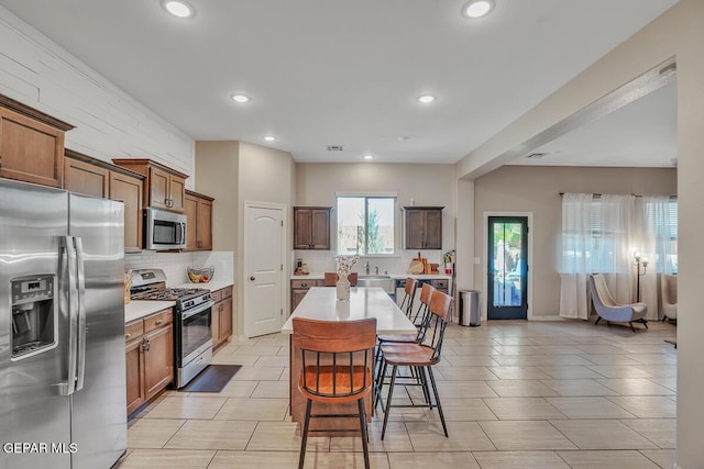14809 Tierra Escape Ave, El Paso, TX 79938 - kitchen with stainless steel appliances, decorative backsplash, a kitchen breakfast bar, light countertops, and recessed lighting